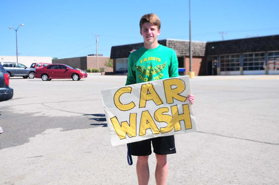 Holding up a sign for the soccer car wash, sophomore Joe Stokes tries to get attention from the passing cars on the busy street. Stokes was on junior varsity this year.