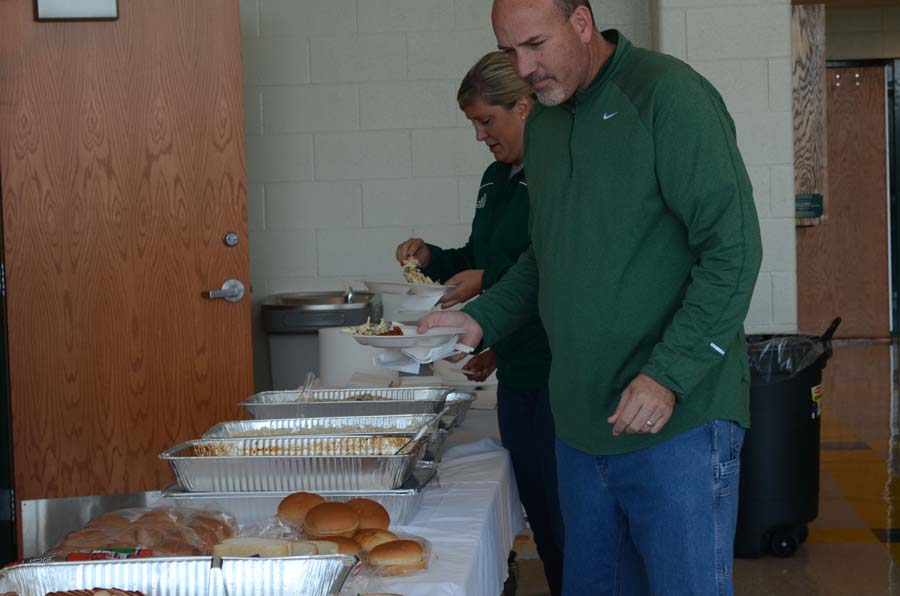 Serving themselves a plate, golf coach Mr. Henry and soccer coach Mrs. Dosland enjoy lunch in the gym lobby with their fellow staff members and coaches. The coaches apprecation lunch was held on OCtober 17th.