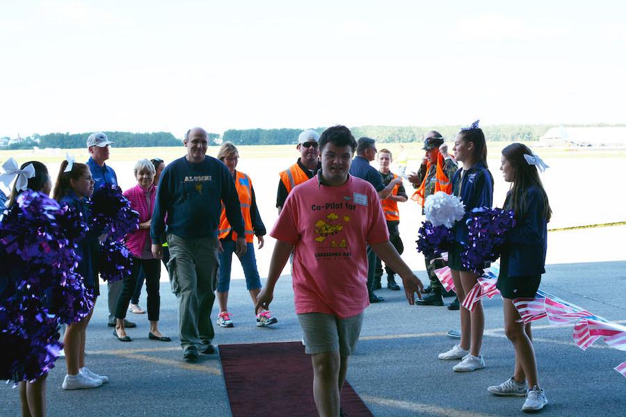 After his plane ride, sophomore Wesley Hansen walks through a row of cheerleaders cheering for him.