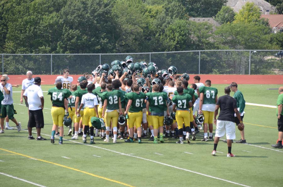 Varsity football team joins together in a huddle at the end of the first team scrimmage in preparation for the upcoming season.