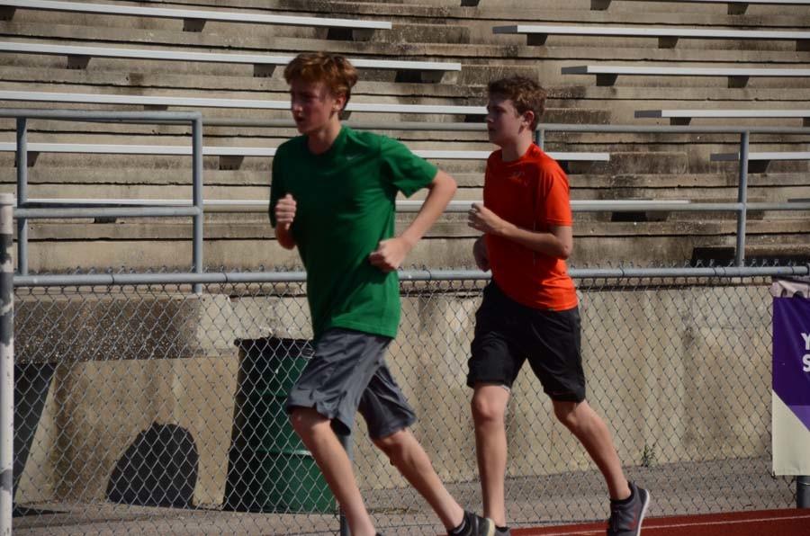 Freshmen Jason Giannola and Sam Caldwell run around the track during warmups for cross country. 