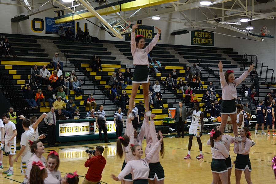 As the boys varsity starting line-up is called out, the cheerleaders are pumping up the crowd with their stunts. 