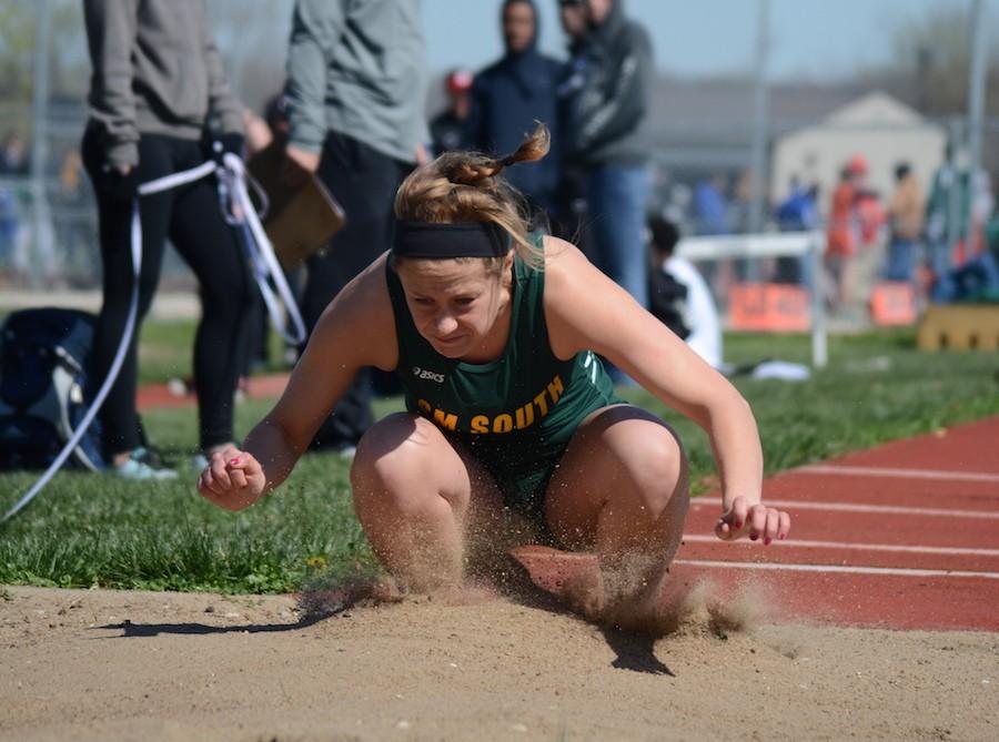 Jumping into the sand pit with her jumping spikes, senior Gretchen Fiebig tackles her triple jump event at South Relays. 