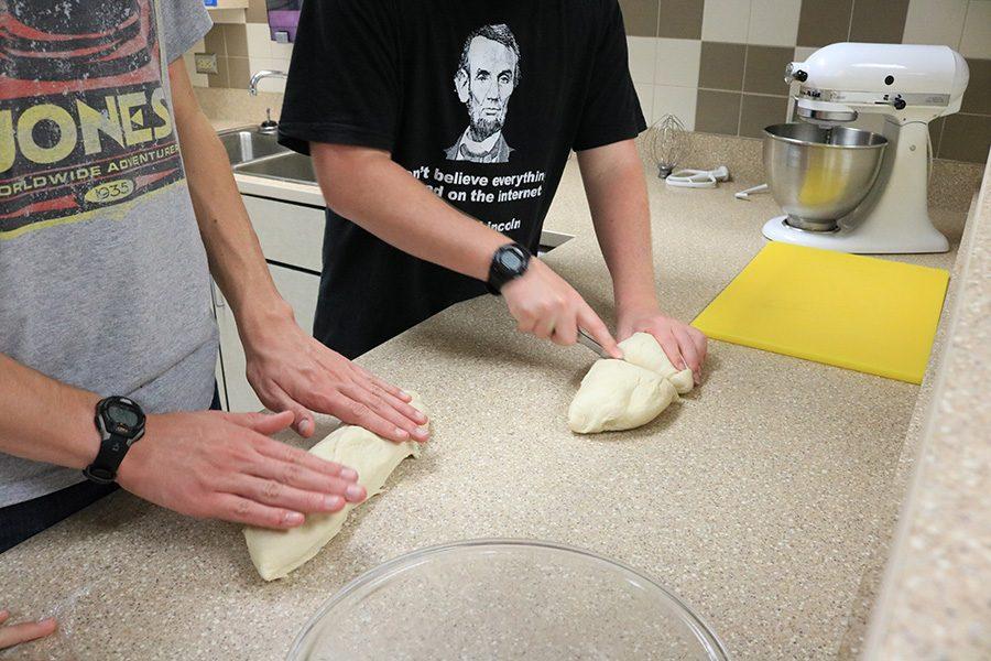 Juniors Peter Sears and Nicholas James cut dough into pieces and start rolling them into long strips in order to twist them into the iconic pretzel shape. Pretzel making was a tradition for Souths orchestra in the days leading up to Oktoberfest. 
Photo by Cassandra Awad