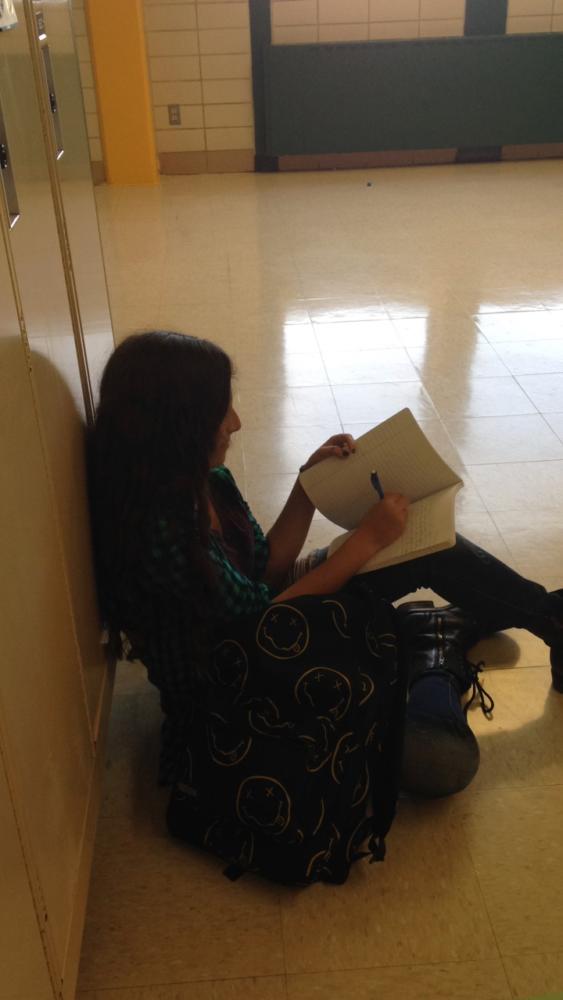 At the end of a stressful day, freshman Sofia Dadkhah writes while sitting in the hallway.