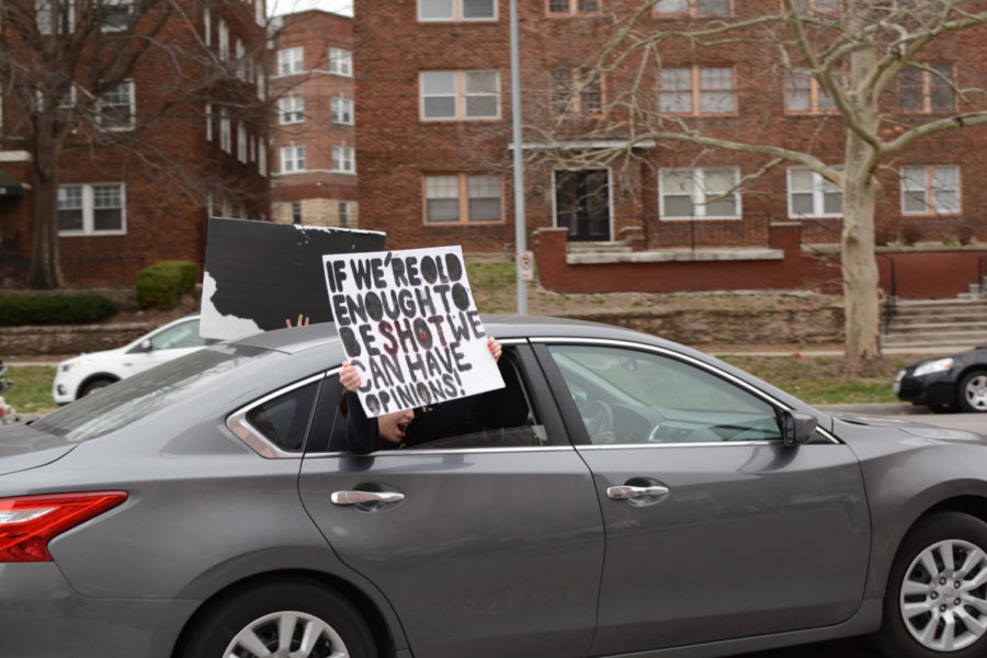 A student holds a sign outside of a car window.