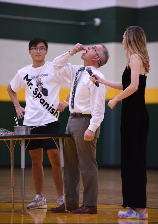 Athletic Director John Johnson eats a spicy noodle prepared by senior Young Woo Chang. Chang ate an entire pot of the noodles as his talent for the pageant.
