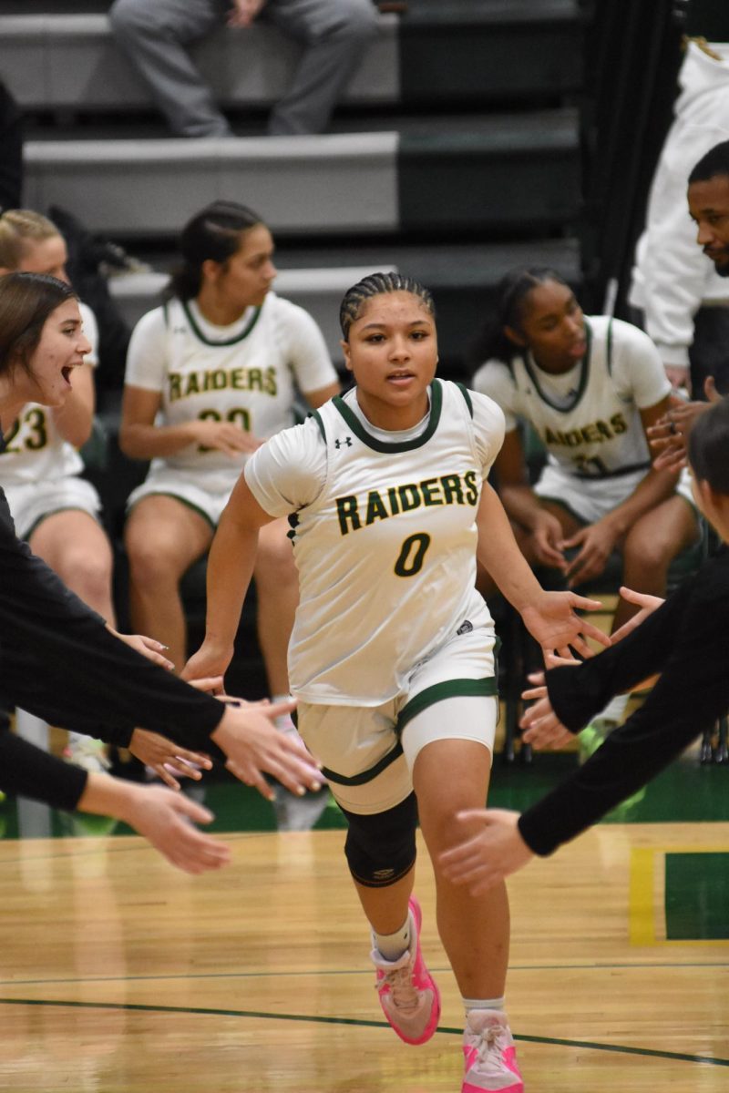 Senior Jocelyn Moore runs onto the court after being announced during the game against SM West on January 5. The game was the first competition back after winter break, taking place Friday before students started class for second semester.