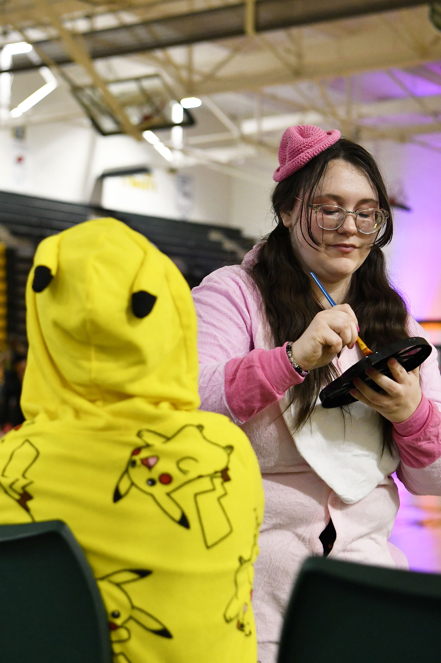 Loading up her brush, senior Samara Rowe, paints a pokeball on a kids hand a kid during Trunk or Treat. Rowe and her journalism classmates offered face painting for the children attending Souths Trunk or Treat, Oct 30.