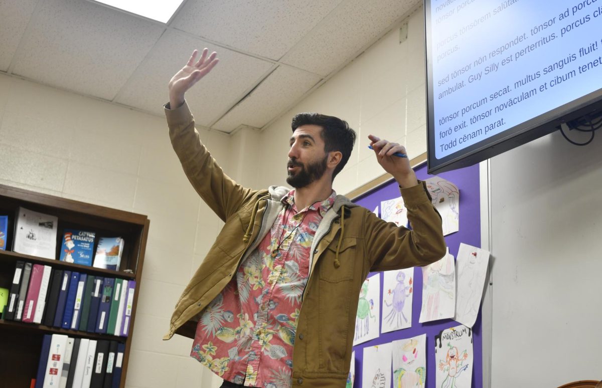 Mr. Wilkins raises his hands to illustrate a point in class.