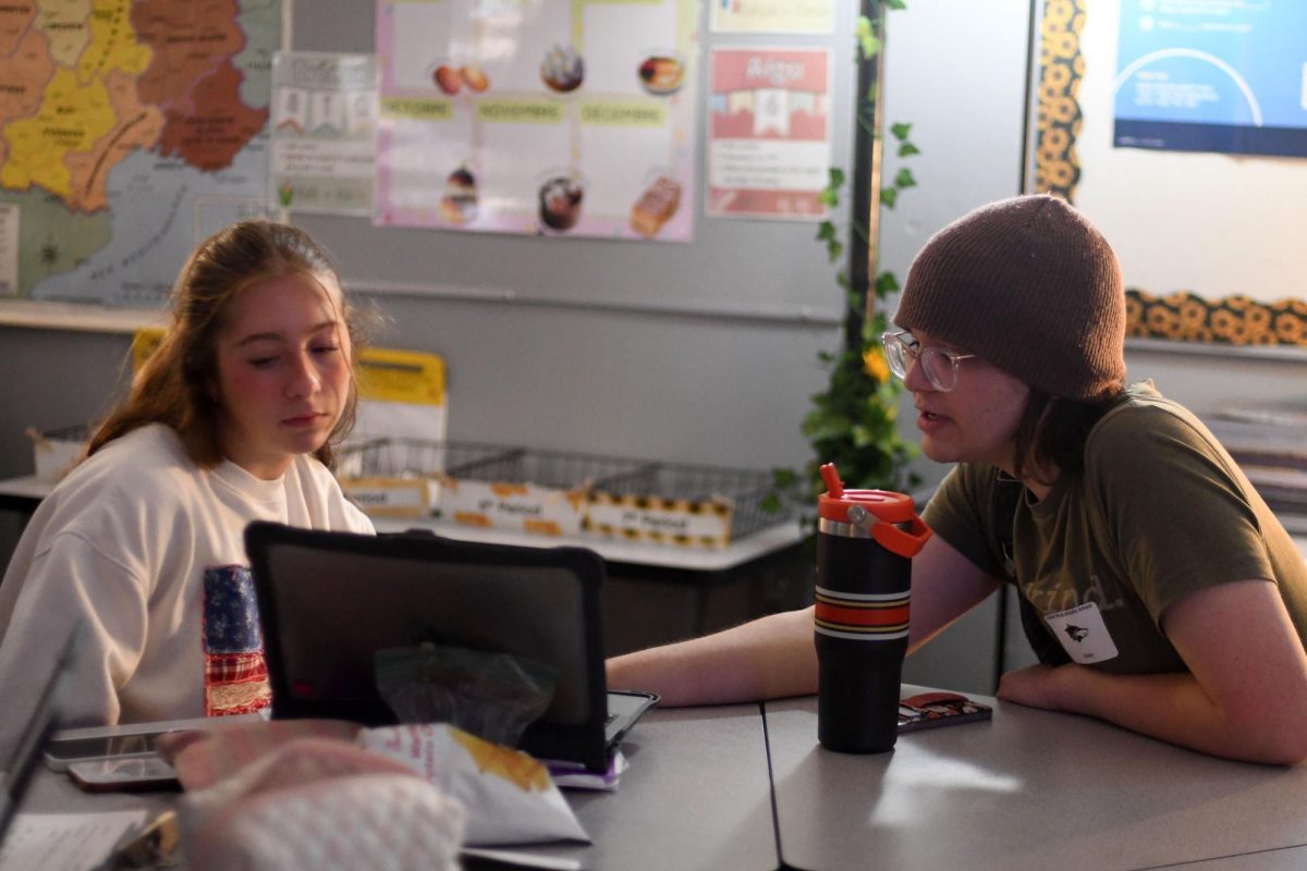 Giving pointers on Adobe Photoshop, senior Asra June, who designs and writes for the newspaper at SMS, helps middle school student Clara Rupp. “It was a really positive experience. They have a really great program,” June said. 