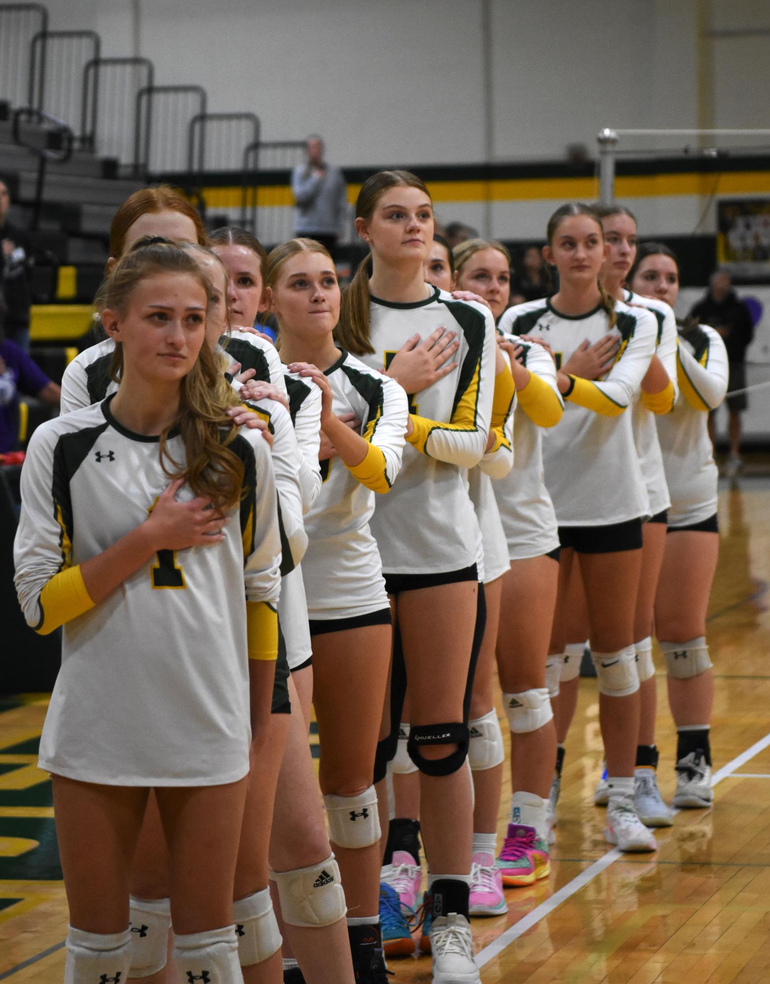 The girls volleyball team stands proudly during the national anthem, with Junior Madeline Dillon among those showing respect and unity before each game. Their commitment to the game and each other is evident from the very start.