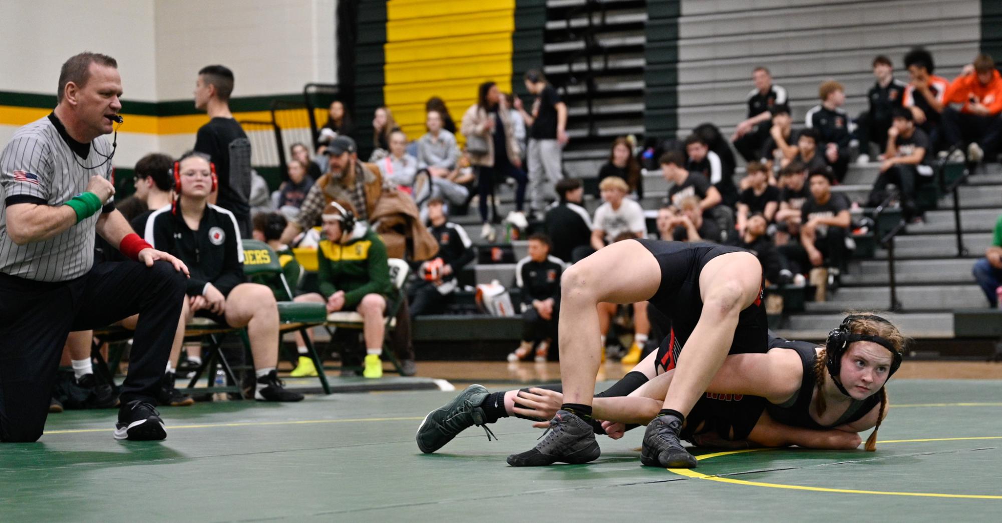 Waiting for the referee to call a pin, sophomore Rachael Wilson wrestles her SMN opponent during districts on January 22. Wilson won the match 11-0 in the 130-pound weight class.