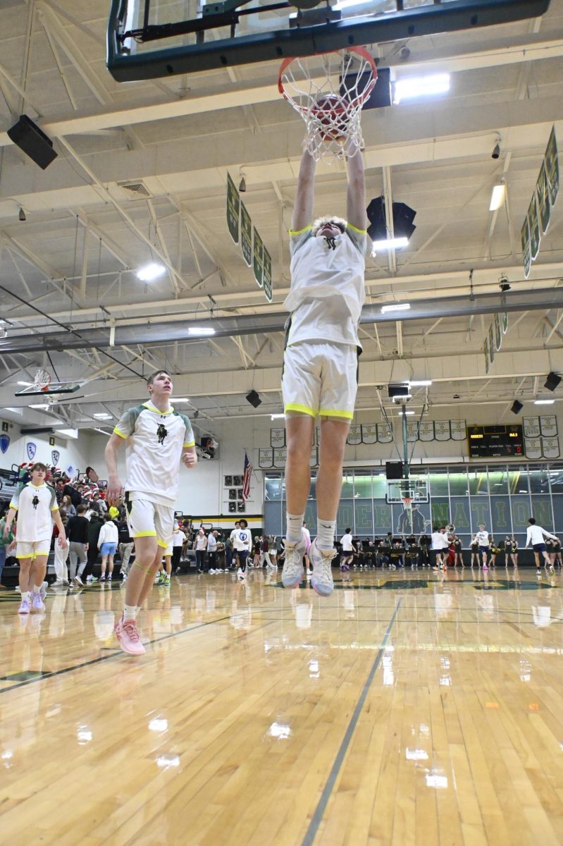 Junior captain Drake Debaun goes up for a dunk in warmups before a game against Olathe west on December 13.