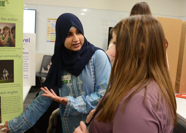 Explaining her photos, senior Manahil Fatima tells junior Emmalee Rich the backstory of her favorite photos at the showcase on Feb 3. 