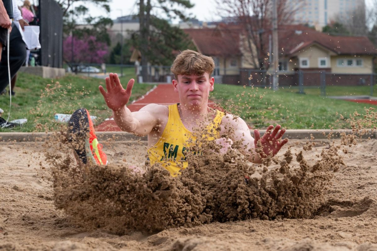 Kicking sand in the air, junior Miles Flint does his long jump during a track meet at South on April 1st.