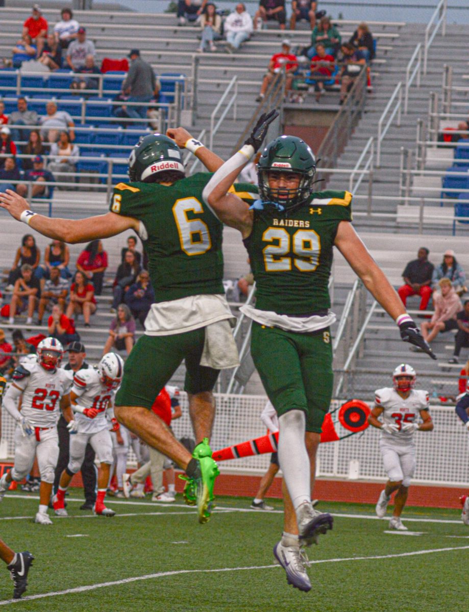 Senior Solomon Hirsch and junior Rowan Minnick celebrate after Minnick forced a fumble during the season opener against Olathe North on Thursday Sept. 4.