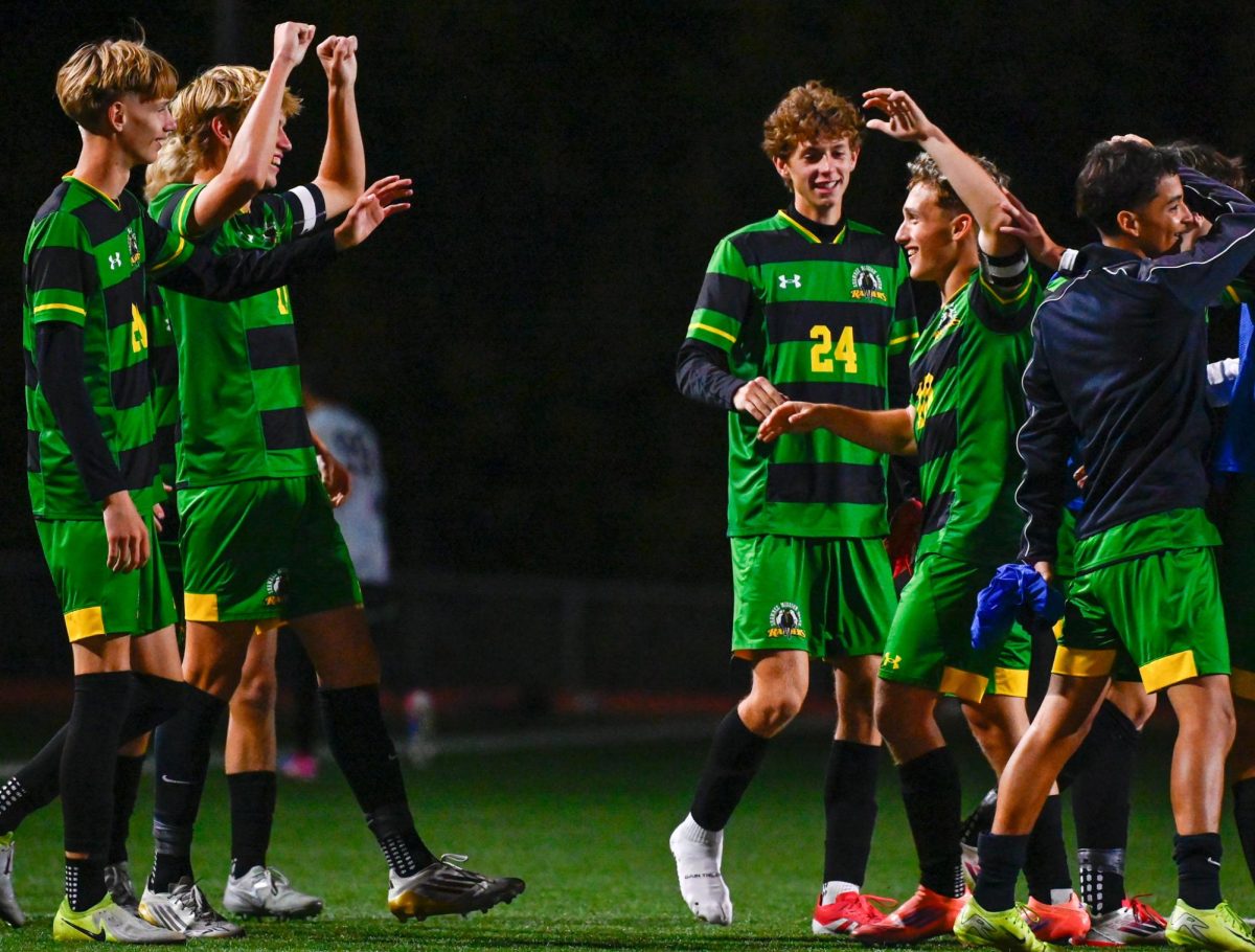 Hands raised, senior Nathanael Lee and junior Owen Jungk celebrate their win against Lawrence Free State High School with a final score of 4-1 at their last home game. The Varsity team is now headed to regionals after the win.