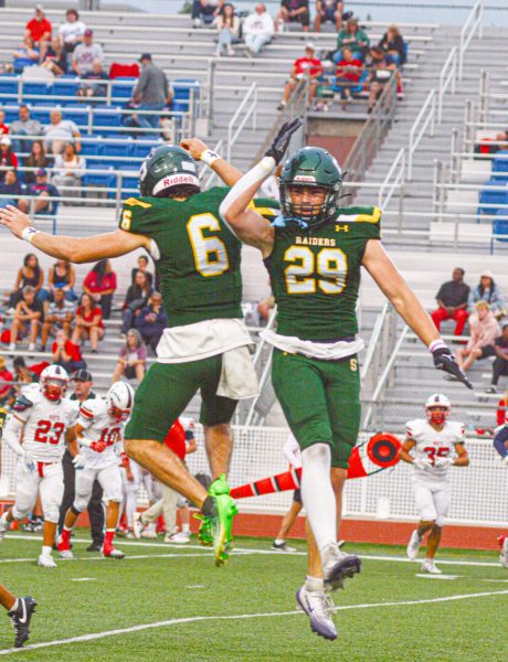 Senior Solomon Hirsch and junior Rowan Minnick celebrate after Minnick forced a fumble during the season opener against Olathe North on Thursday, Sept. 4.