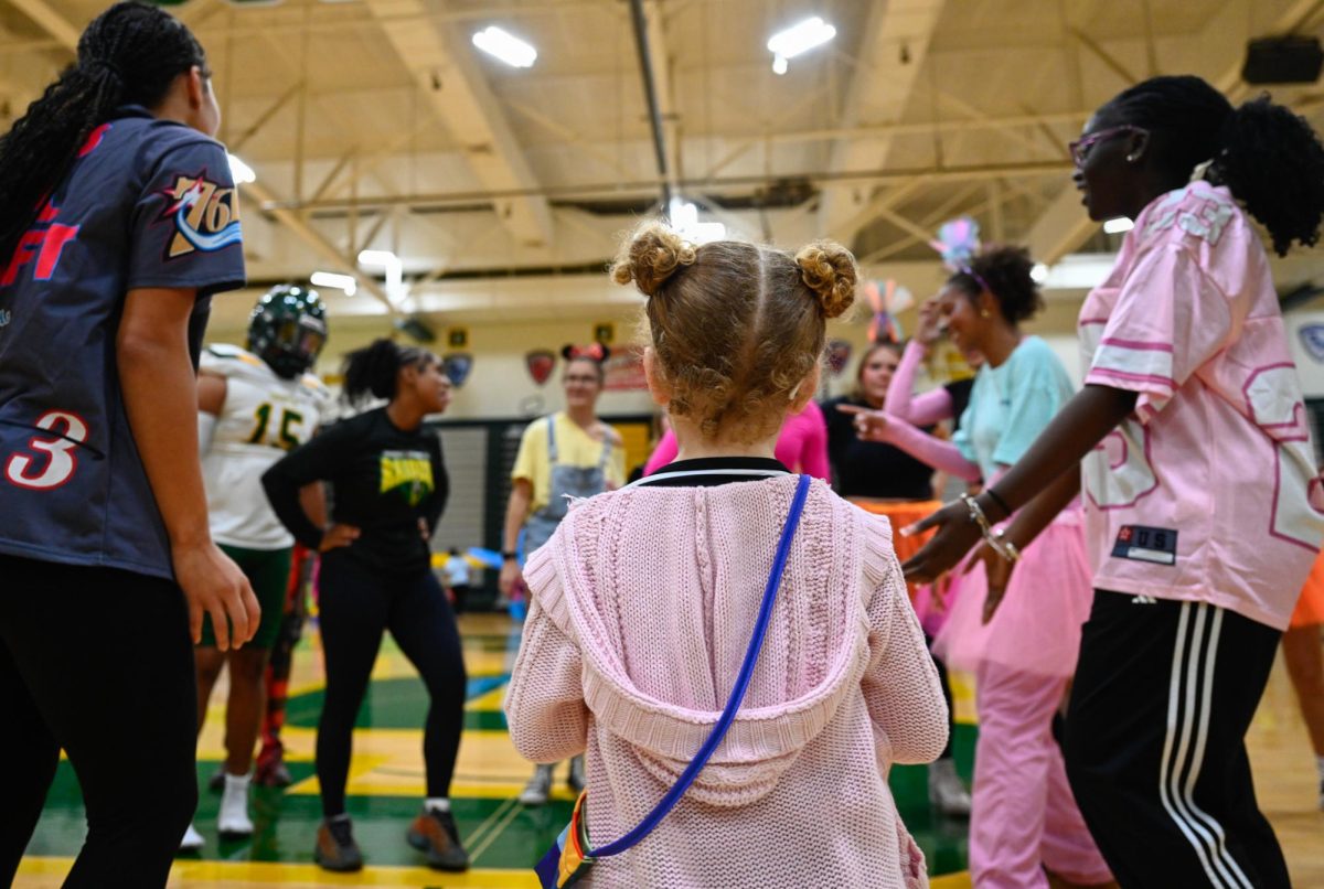 A little girl looks out in wonder at the high school students dancing in a circle during Trunk or Treat. She later joined in.

