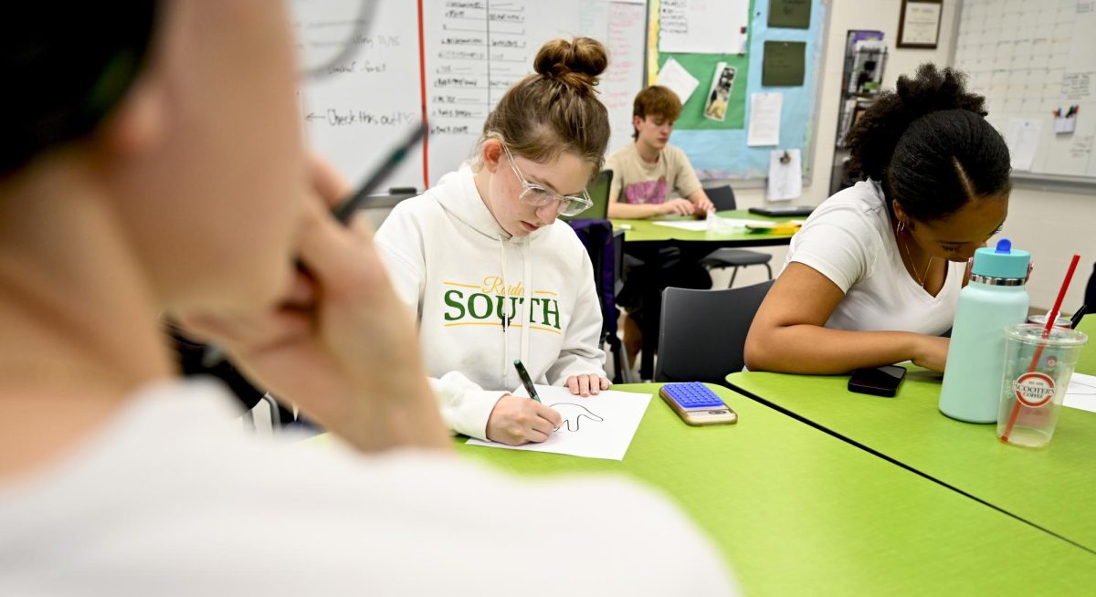 Celebrating Thanksgiving festivities, sophomore Mia Clark and senior Sahara Montgomery decorate hand turkeys as a team building activity in photojournalism class on Nov 20. 